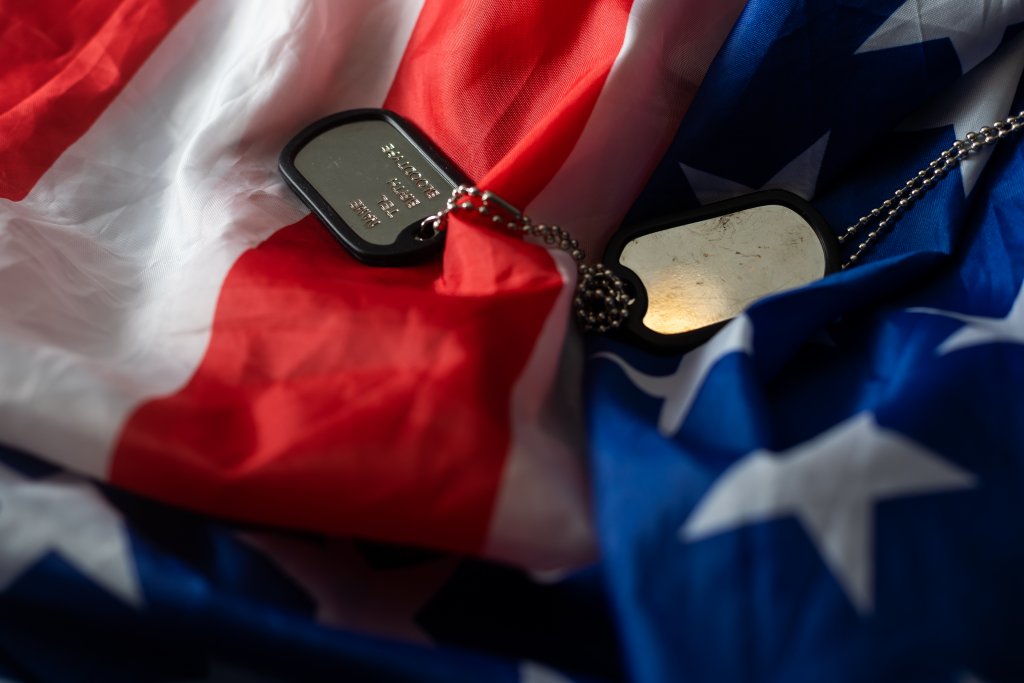 american flag and dog tag of veteran and a solider